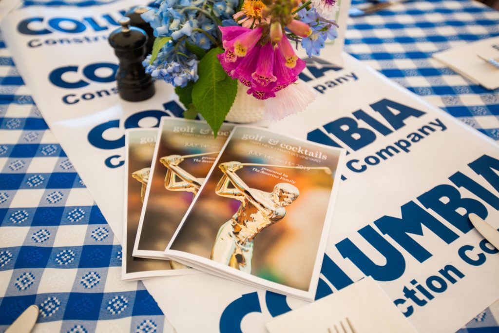 Image of a booklet for MVH golf fundraising tournament on a picnic table with flowers