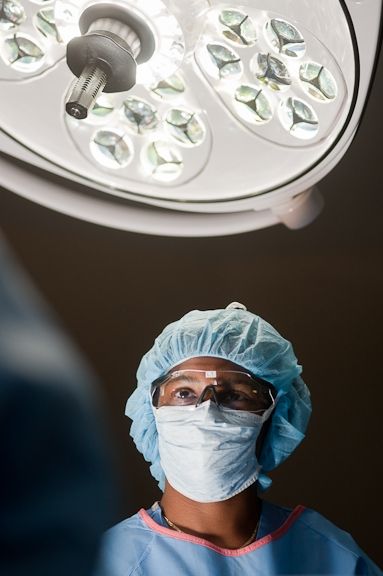 Image of masked doctor standing under a light preparing for surgery